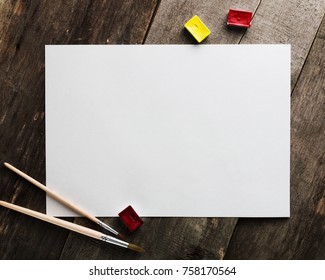 Blank Paper With Watercolor And Brushes On The Wooden Table For Mockups.