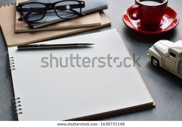 Blank paper for\
writing business ideas, Close-up view table desk with pen, glasses,\
black coffee and model\
car.