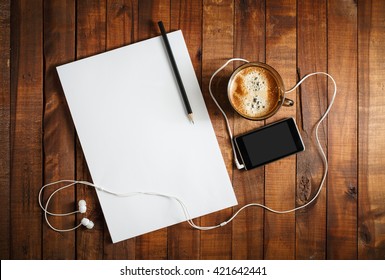 Blank Paperwork Template For Designers. Responsive Design Mockup On Vintage Wooden Background. Paper, Letterhead, Coffee Cup, Smartphone, Pencil And Headphones On Wooden Table Background. Top View.