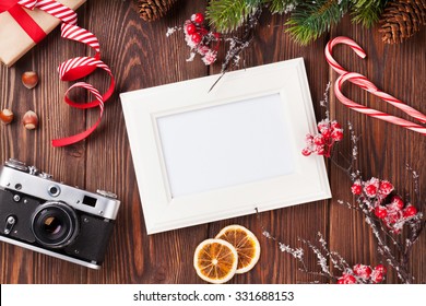 Blank Photo Frame With Christmas Gift Box, Pine Tree And Camera On Wooden Table. Top View