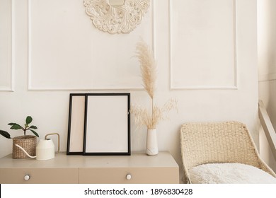 Blank Photo Frame With Copy Space On Table. Fluffy Reeds, Pampas Grass Bouquet, Home Plant, Rattan Chair Against White Wall. Comfortable Modern Interior Design. Stylish Bright Living Room.