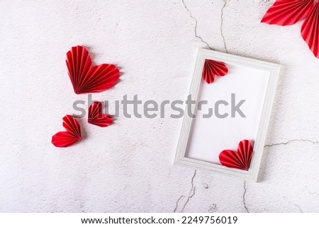 Blank photo frame and DIY paper hearts and leaves on plaster. Home decor.