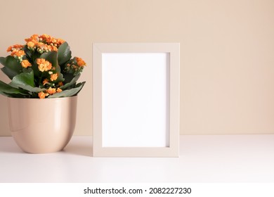 Blank Photo Frame Mockup And Kalanchoe Plant With Orange Flowers In Pot On Beige Background.