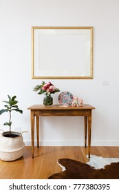 Blank Picture Frame Above A Side Table With Flowers And Pot Plant