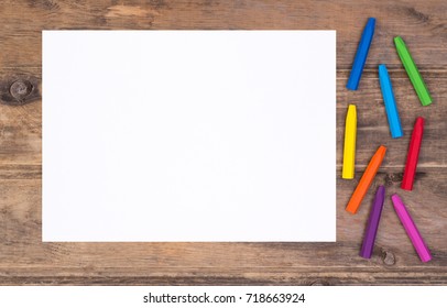 Blank Piece Of Paper With Colorful Crayons On  Kid's Desk, Top View With Copy Space