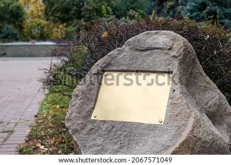 Blank plaque on the stone. Bronze memorial plaque in the park. Empty sign board on the wall.
