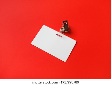 Blank Plastic Badge Mockup On Red Paper Background. Empty Name Tag Mock Up. Space For Text.