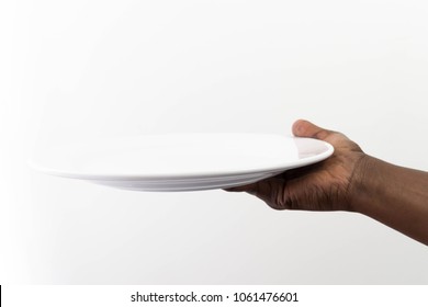 Blank plate on African American hand One white kitchen plate tray on dark brown skin human hand on white background Cook's hand holding an empty plate female hand plate serving