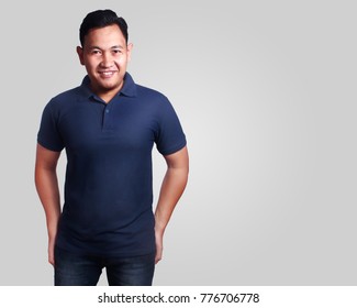 Blank polo shirt mock up, front  view, isolated on grey. Asian male model wear plain dark blue tshirt mockup. Clothes uniform design presentation for print