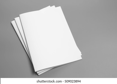 Prázdný portrét A4. časopis brožury izolovaný na šedé, proměnlivé pozadí/ bílý papír izolovaný na šedém