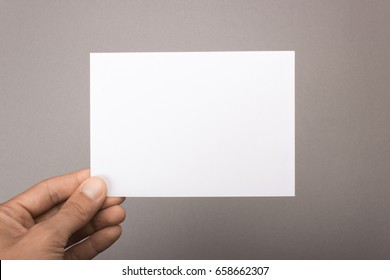 Blank Postcard In Hand On A Gray Background. Leaflet A6 Mockup