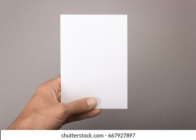 Blank Postcard In Hand On A Gray Background. Leaflet A6 Mockup