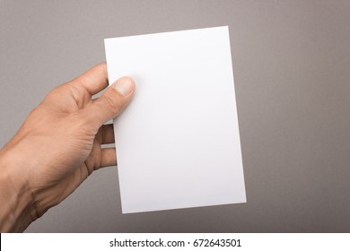 Blank Postcard In Hand On A Gray Background. Leaflet A6 Mockup