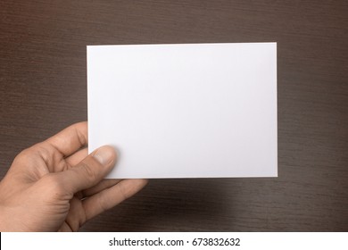 Blank Postcard In Hand On A Gray Background. Leaflet A6 Mockup