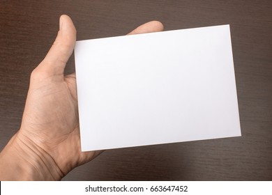 Blank Postcard In Hand On Wooden Background. Leaflet A6 Mockup