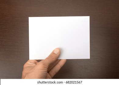 Blank Postcard In Hand On Wooden Background. Leaflet A6 Mockup