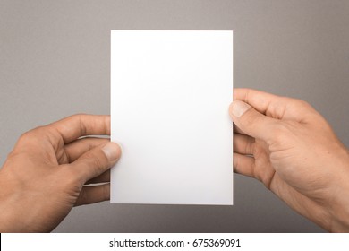 Blank Postcard In Hands On A Gray Background. Leaflet A6 Mockup