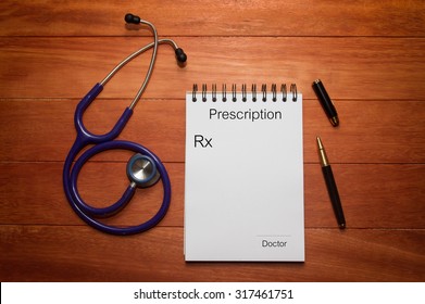 Blank Prescription Of Doctor With Stethoscope And Black Ink Pen On Wooden Table, Can Be Refilled With Words 