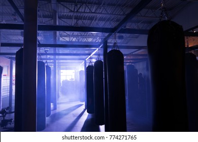 Blank punching bags in misty cinematic boxing gym and film set. - Powered by Shutterstock