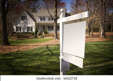 Blank Real Estate Sign In Front Of A White Frame Home With A Nice Yard.