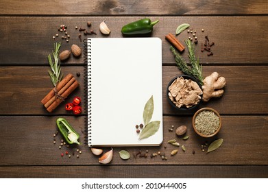 Blank recipe book and different ingredients on wooden table, flat lay. Space for text - Shutterstock ID 2010444005