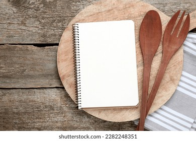 Blank recipe book and kitchen utensils on old wooden table, flat lay. Space for text