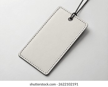 Etiqueta de cuero rectangular en blanco con esquinas redondeadas y cuerda negra sobre una superficie gris claro – Concepto de marca minimalista