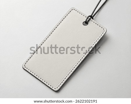 Blank rectangular leather tag with rounded corners and black string on a light gray surface – Minimalist Branding Concept
