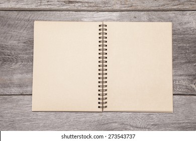 A blank recycled paper scrapbook sits on a rustic wooden background. 