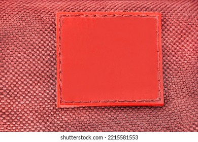Blank red square rubber patch stitched on fabric closeup