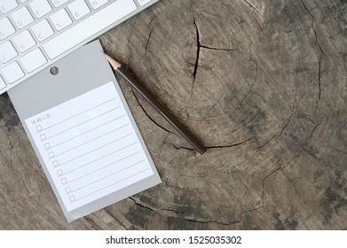 Blank reminder to do list with pencil and white computerkeyboard on wooden background.