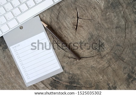 Blank reminder to do list with pencil and white computerkeyboard on wooden background.