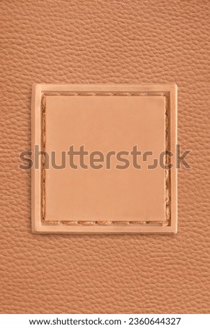 Blank rubber patch stitched on brown leatherette background closeup