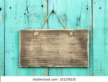 Blank rustic wooden sign hanging on washed out teal blue distressed antique wood background; color copy space - Powered by Shutterstock