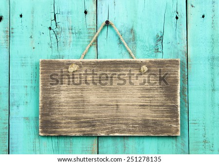 Blank rustic wooden sign hanging on washed out teal blue distressed antique wood background; color copy space