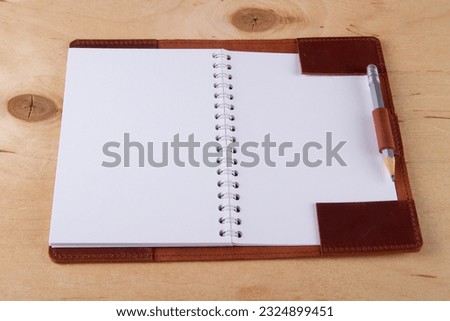 Blank scratchpad in leather cover with graphite pencil lie on wooden desk