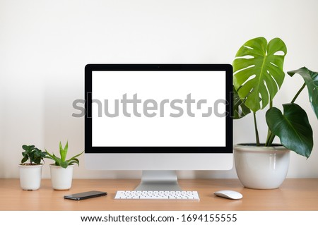 Blank screen of All in one computer, keyboard, mouse, monstera plant pot and small plant pots  on wooden table