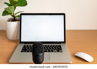 Blank Screen Of Laptop Computer With Microphone And Fiddle Fig Tree Pot On Wooden Table