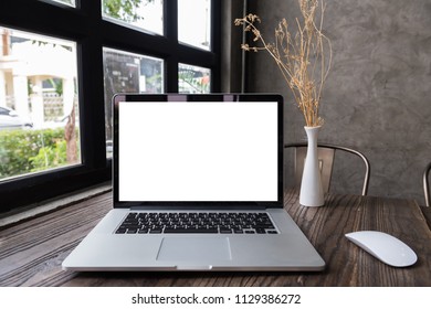 blank screen laptop computer with mouse on wooden table, dark background - Shutterstock ID 1129386272