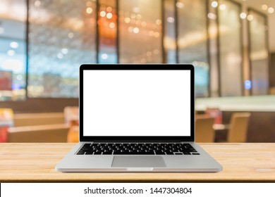 Blank screen laptop computer on wood table top with blur cafe restaurant with abstract bokeh light defocused background