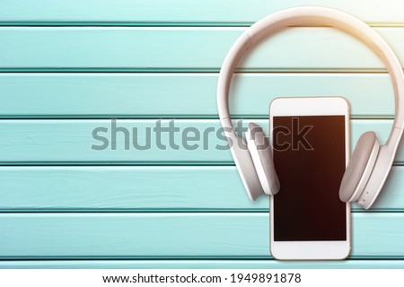 Blank screen modern smartphone on the desk with headphones