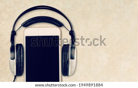 Blank screen modern smartphone on the desk with headphones