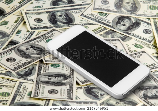 Blank screen smartphone which is is placed on\
the pile of dollar\
banknotes.