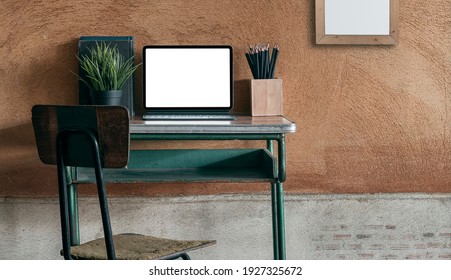 Blank screen tablet computer on wooden desk in vintage classroom.