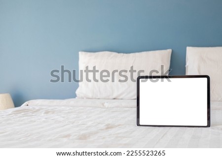 Blank screen tablet on bed in bedroom.