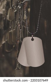 A Blank Set Of Dog Tags Hanging Against A A Collection Of Fallen Soldier Tags. Main Tag Is Blank For Placement Of Copy. 