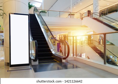 blank showcase billboard or advertising light box for your text message or media content with escalator in modern department store shopping mall, shopping center, commercial and marketing concept