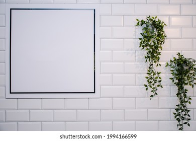 Blank Sign On A White Brick Wall With Some Plants. Ideal For Logo Mock Up