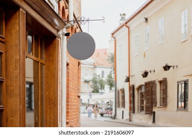 Blank Signboard Mock Up, On The Facade In Old Town. Copy Space For Your Store Sign Or Logo. Modern Empty Outdoor Signage, Mockup To Add Company Logo. Gray Round Store Signboard.