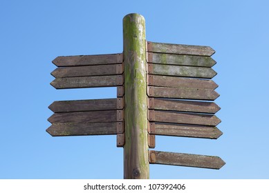 Blank signpost made from weathered wood with 15 arrows against a blue sky